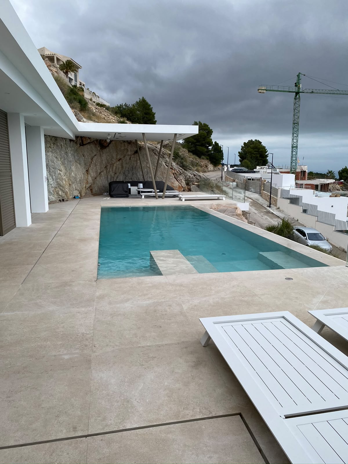 Bassengterrasse foran hvit villa mot fjellveggen