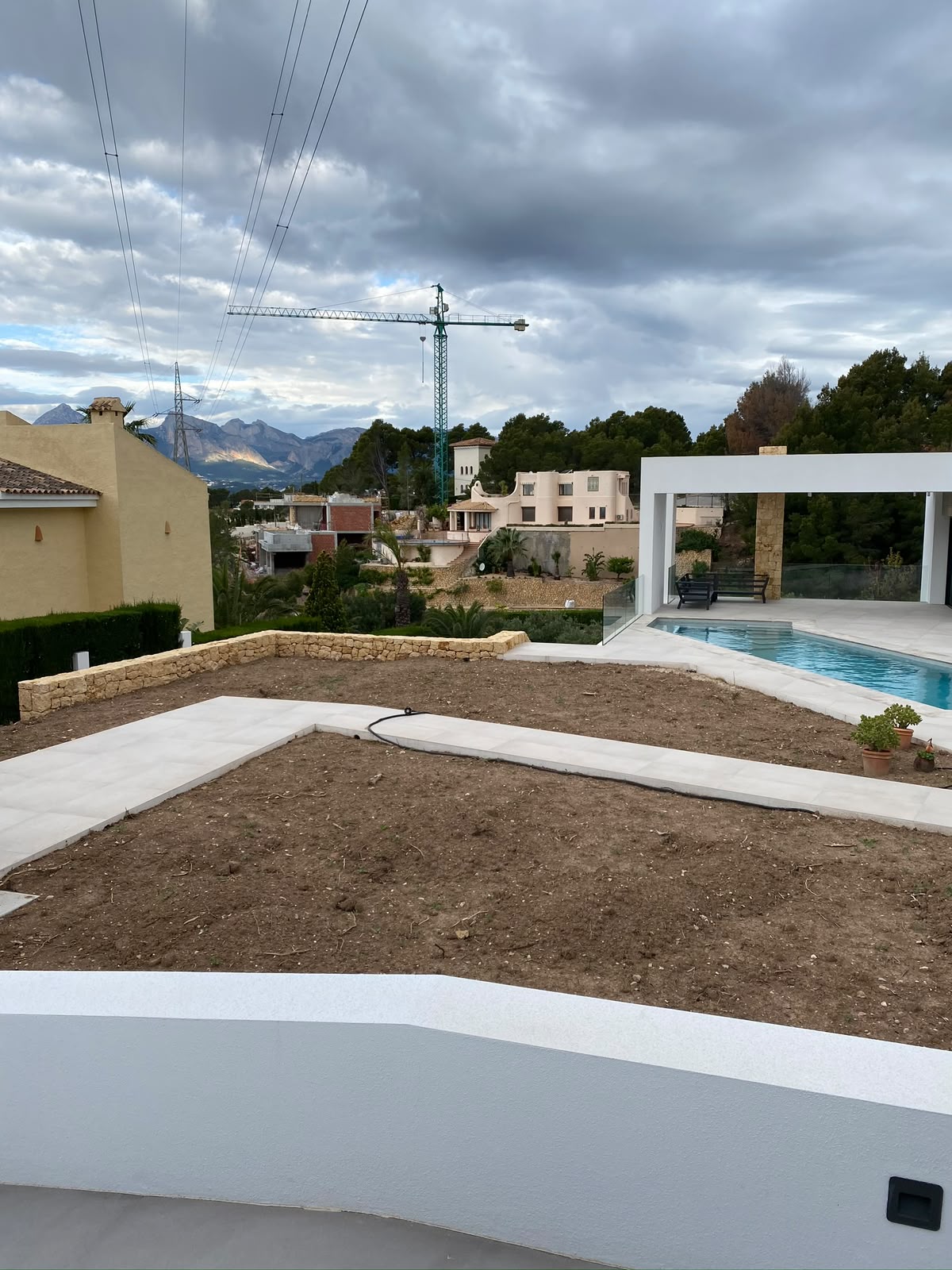 Hage under anlegg med natursteinmur, gangbaner i heller, pergola og basseng