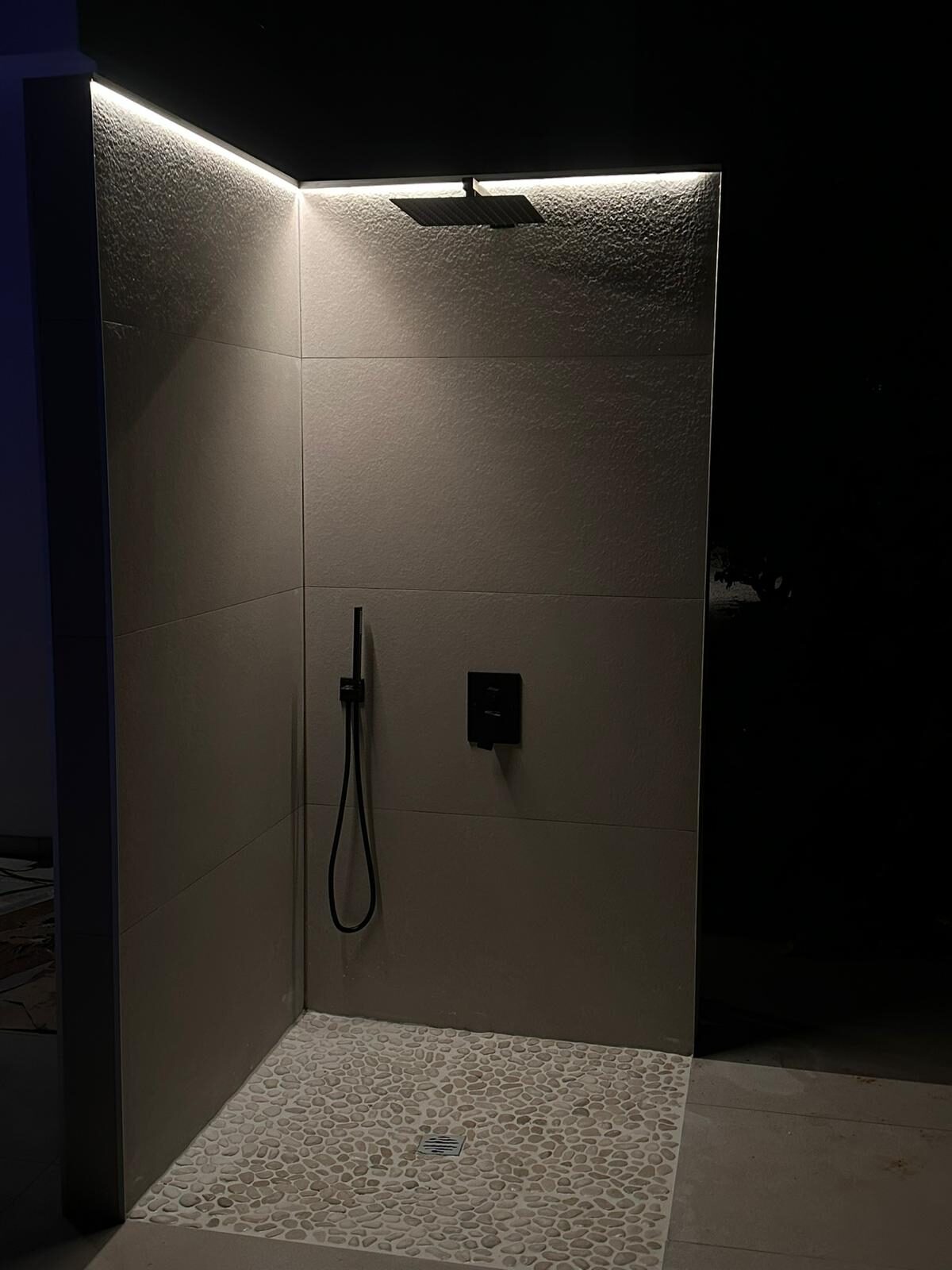 Detalj av regndusj med varmt LED-lys mot teksturert flis