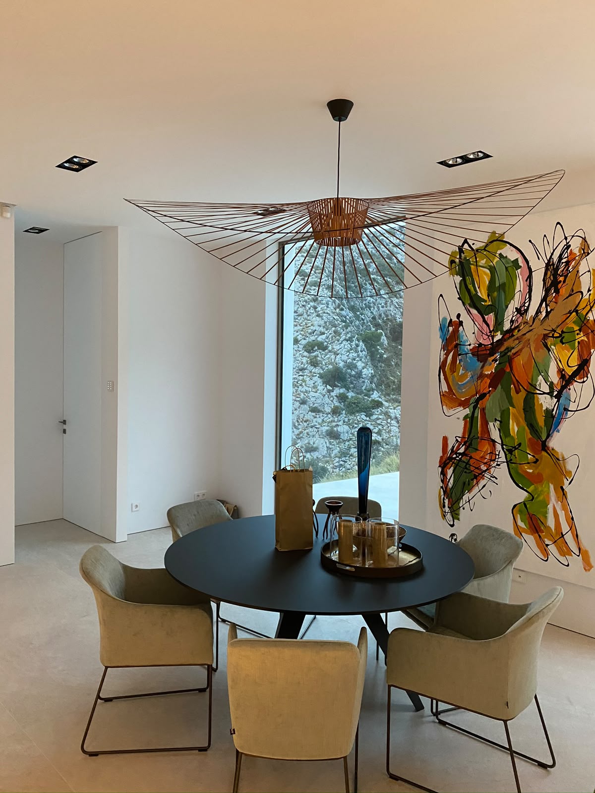 Spisestue med rundt bord, designlampe og stort kunstverk på veggen